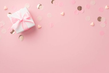 Cinsiyet partisi konsepti. Beyaz hediye kutusunun üst görüntüsü küçük kalpler ve kopyalanmış pastel pembe arka planda parlayan konfetiler.