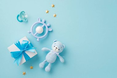 Bebek oğlan konsepti. Hediye kutusunun üst görüntüsü daha rahatlatıcı çıngırak örgü oyuncak ve izole edilmiş pastel arka planda altın yıldızlar.