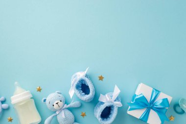 Bebek aksesuarları konsepti. Hediye kutusunun en üstteki fotoğrafı oyuncak ayıcıklar oyuncak bebek emziği şişesi ve izole edilmiş pastel mavi arka planda altın yıldızlar.