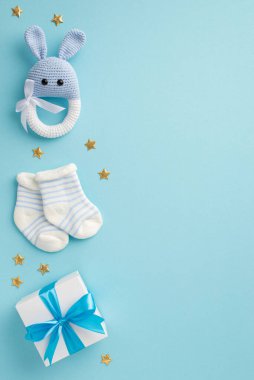 Bebek oğlan konsepti. Üstten bakınca hediye kutusu çoraplarının dikey fotoğrafı örülmüş çıngıraklı tavşan oyuncağı ve izole edilmiş pastel mavi arka planda altın yıldızlar.