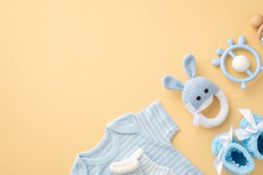 Bebek aksesuarları konsepti. Mavi bebek giysisi çoraplarının üst görüntüsü çoraplar örülmüş tavşan çıngıraklı oyuncak ve izole edilmiş pastel bej arkaplan üzerinde iple bağlanmış