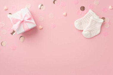 Cinsiyet partisi konsepti. Beyaz hediye kutusunun üst görüntüsü. Yay, küçük kalpler, küçük çoraplar ve izole edilmiş pastel pembe arka planda parlak bir konfeti. Boş alan.