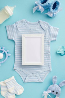 Bebek oğlan konsepti. Üst görüntüde vücut giysisinin dikey fotoğrafı. Fotoğraf çerçevesi, bağcık örgüsü, oyuncak çoraplar süt şişesi ve izole edilmiş pastel mavi arka planda emzik.