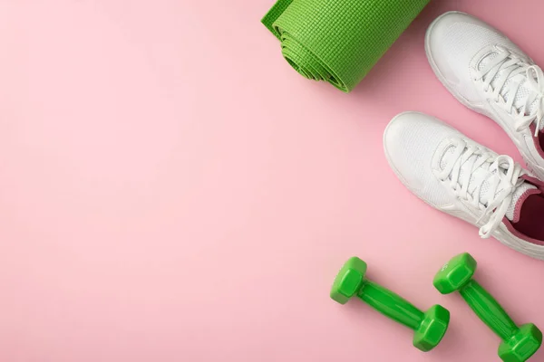Fitness concept. Top view photo of white sports shoes exercise mat and green dumbbells on isolated pastel pink background with empty space