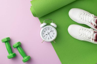 Spor aksesuarları konsepti. Yeşil egzersiz paspasının üzerinde beyaz spor ayakkabıları ve izole edilmiş pastel eflatun arka planda çalar saat.