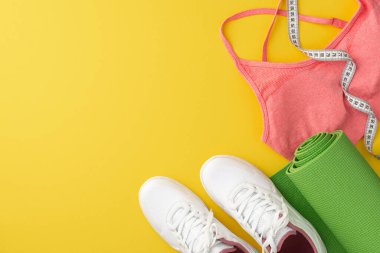 Spor aksesuarları konsepti. Üst görünüm pembe spor ayakkabılı spor ayakkabılı spor minderi ve izole edilmiş sarı arkaplanlı mezura boş alan