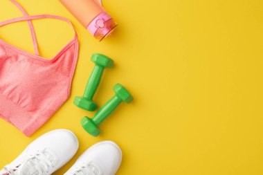 Fitness konsepti. Üst görüntüde pembe spor fotoğrafları su dambılları şişesi ve beyaz ayakkabılar izole edilmiş sarı arka planda