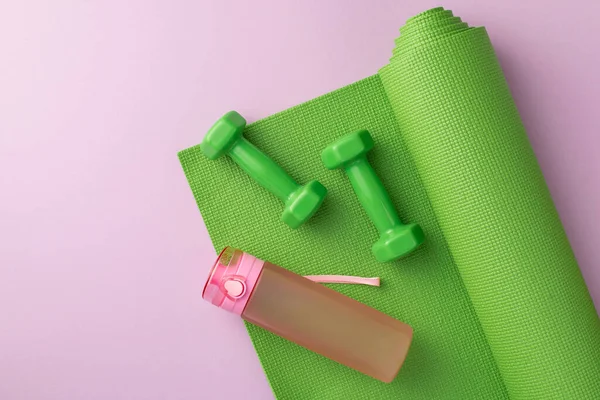 スポーツアクセサリーのコンセプト 緑の運動マットのダンベルと孤立したパステルライラックの背景に水のピンクのボトルのトップビューの写真 — ストック写真