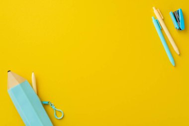 Okul konseptine geri dönelim. Okulun en iyi görüntüsü mavi kalem kutulu zımba ve boş alan ile izole edilmiş sarı arka planda kalemler içeriyor.