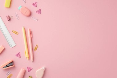 Okul malzemeleri konsepti. Kırtasiye kalemlerinin üst görünüm fotoğrafı cetvel zımba klasörü yuvarlak düzeltme bandı ve kopyalanmış pembe arkaplan üzerine ananas şekilli silgi.