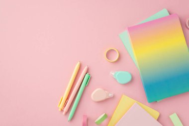 School accessories concept. Top view photo of colorful stationery rainbow color diary pens round correction tape ruler and adhesive tape on isolated pink background