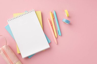 Okul konseptine geri dönelim. Okul malzemelerinin en üst görüntüsü spiral not defteri renkli kalem kutusu ve izole edilmiş pembe arka planda boş alan bandı.