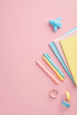 Okul konseptine geri dönelim. Okul aksesuarlarının dikey fotoğrafı. Renkli günlükler. Yapışkan bant ve uçak şekilli bileyiciler.