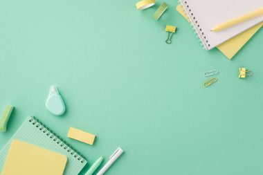 Back to school concept. Top view photo of school accessories notebooks pens round correction tape binder clips adhesive tape and sticky bookmarks on isolated pastel green background with copyspace