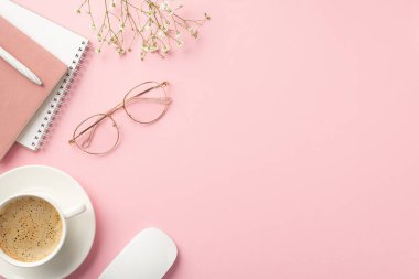 İş konsepti. Çalışma alanının en üst görüntüsü notlar kalem fincanı bilgisayar faresi stili bardaklar ve izole edilmiş pastel pembe arka planda beyaz çigila çiçekleri boş alan