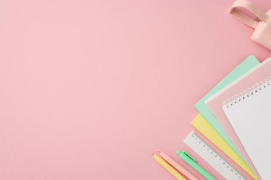 Okul konseptine geri dönelim. Renkli metin kitaplarının üst görünüm fotoğrafı. Cetvel, cetvel ve pembe kalem kutusu, izole edilmiş pembe arka plan, boş alan.