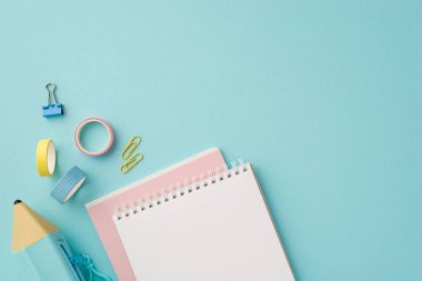 Back to school concept. Top view photo of school supplies stack of notepads blue pencil-case adhesive tape and binder clips on isolated pastel blue background