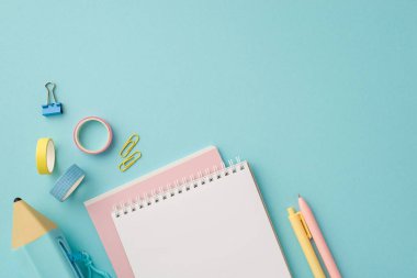 Back to school concept. Top view photo of school accessories stack of planners pens blue pencil-case adhesive tape and binder clips on isolated pastel blue background