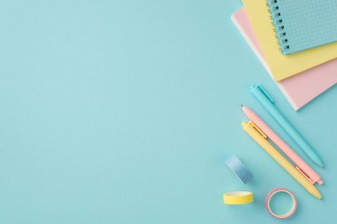 Okul malzemeleri konsepti. Renkli kırtasiye kağıtlarının üst görünüm fotoğrafı yapıştırıcı bant ve kalemler izole edilmiş pastel mavi arkaplandalar ve kopyalanmış mavi arkaplan