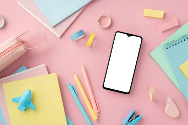 Back to school concept. Top view photo of smartphone notepads pens plane shaped sharpener adhesive tape stapler round correction tape pencil-case erasers on isolated pink background with copyspace