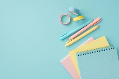 Back to school concept. Top view photo of colorful school supplies adhesive tape pens and notepads on isolated pastel blue background