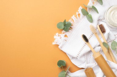 Çevre dostu kavram. Kaplıca aksesuarları diş fırçaları diş macunu kavanozu beyaz havlu ve izole edilmiş bej arkaplan üzerinde okaliptüs.