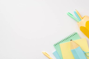Okul konseptine geri dönelim. Okul aksesuarlarının üst görünümü mavi kalem kutusu kopya kitapları ve izole edilmiş beyaz arka plandaki kalemler için sarı stand