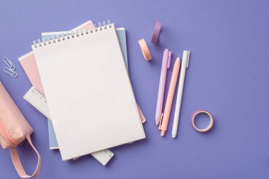 Okul konseptine geri dönelim. Üst görünüm fotoğraf yığını defter kalem yapışkan bant cetvel ve izole edilmiş eflatun arkaplan üzerinde pembe kalem kutusu boş alan