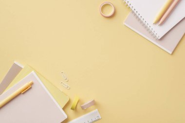 Back to school concept. Top view photo of stationery diaries pens ruler clips and adhesive tape on isolated pastel yellow background with copyspace