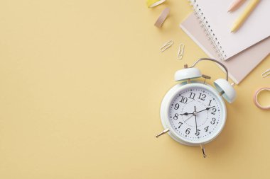 Okul konseptine geri dönelim. Okul malzemelerinin üst görüntüsü alarm notları kalem klipleri ve izole edilmiş pastel sarı arka planda boş alan ile yapıştırıcı bant.