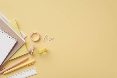 Okul konseptine geri dönelim. Okul malzemelerinin en üst görüntüsü notlar cetvel klipleri ve izole edilmiş pastel sarı arkaplan üzerine yapıştırıcı bant