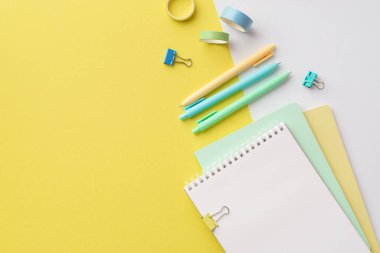 School concept. Top view photo of school supplies notebooks colorful pens binder clips and adhesive tape on bicolor yellow and white background with copyspace