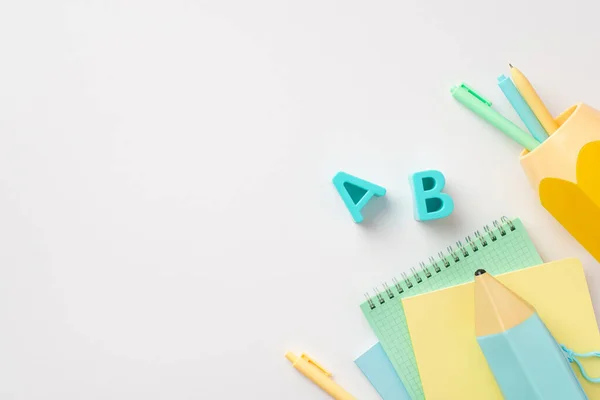 Back to school concept. Top view photo of school accessories plastic alphabet letters blue pencil-case notebooks and stand for pens on isolated white background with copyspace