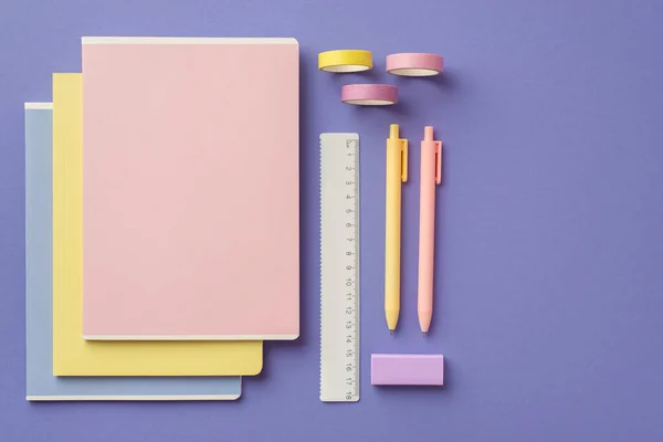 Back to school concept. Top view photo of colorful school supplies stack of notebooks pens ruler eraser and adhesive tape on isolated violet background