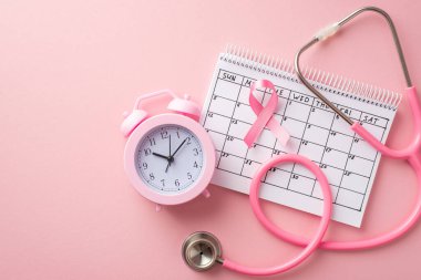 Göğüs kanseri farkındalığı konsepti. Pembe kurdele takviminin üst görüntüsü alarm saati ve izole edilmiş pastel arka planda steteskop.