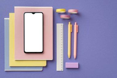 Okul konseptine geri dönelim. Okul malzemelerinin en iyi görüntüsü akıllı telefon, renkli kalemler silgi ve kopyalanmış eflatun arkaplan üzerine yapıştırıcı bant.