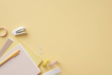Back to school concept. Top view photo of stationery diaries pen ruler clips mini stapler and adhesive tape on isolated pastel yellow background with copyspace