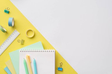 Back to school concept. Top view photo of stationery planners pens ruler adhesive tape and binder clips on bicolor yellow and white background with empty space