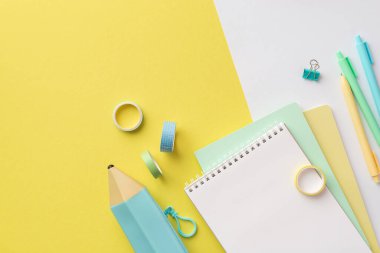 Back to school concept. Top view photo of colorful school supplies blue pencil-case stack of planners pens binder clips and adhesive tape on bicolor yellow and white background with empty space
