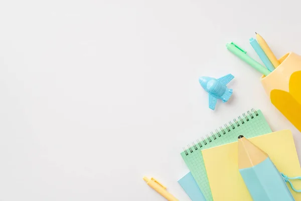 Back to school concept. Top view photo of school supplies plane shaped sharpener blue pencil-case notepads and stand for pens on isolated white background with empty space