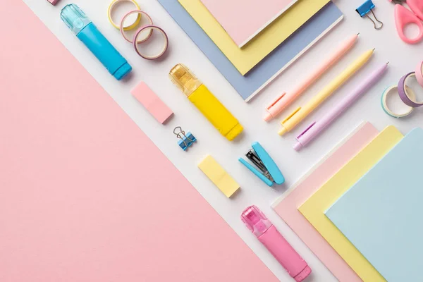 Back to school concept. Top view photo of colorful school supplies diaries correction pens stapler binder clips erasers and adhesive tape on bicolor white and pink background with copyspace