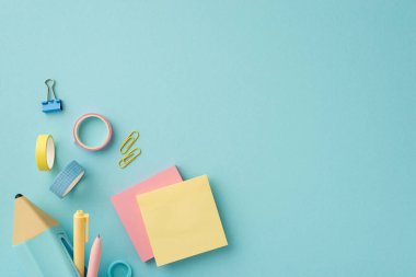 Back to school concept. Top view photo of colorful stationery blue pencil-case with pens sticky note paper adhesive tape and binder clips on isolated pastel blue background with copyspace