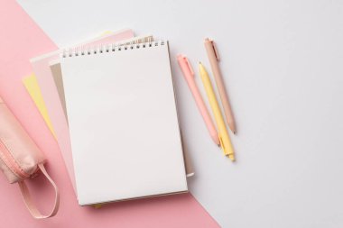 School supplies concept. Top view photo of pink and yellow stationery stack of planners pens and pencil-case on bicolor pink and white background with empty space
