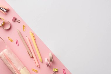 Okul aksesuarları konsepti. Pembe ve sarı kırtasiye kalemlerinin en üstteki fotoğrafı mini zımba zımbası klipsleri yapıştırıcı bant ve kalem kılıfı iki renkli pembe ve beyaz arka plan ve kopyalama alanı