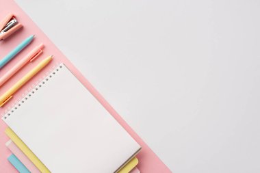 Okul konseptine geri dönelim. Renk kırtasiyesinin en üst görünümü kopya defterleri kalemler ve bicolor beyaz ve pembe arkaplan üzerine mini zımba boş alan