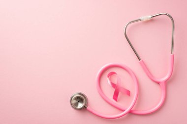 Göğüs kanseri farkındalığı konsepti. Üstten bakınca pembe saten kurdele ve steteskopun fotosu izole edilmiş pastel pembe arka planda kopyalanmış.