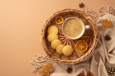Autumn aesthetic concept. Top view photo of wicker tray with cup of frothy cocoa cookies dried orange slices anise yellow maple leaves scarf and pine cone on isolated beige background