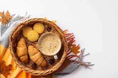 Autumn aesthetic concept. Top view photo of wicker tray with cup of frothy coffee croissants cookies anise yellow maple leaves and plaid on isolated white background