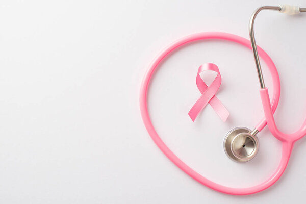 Top view photo of pink ribbon symbol of breast cancer and stethoscope on isolated white background with empty space
