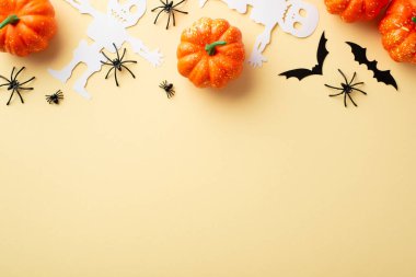 Halloween party concept. Top view photo of pumpkins spiders skeleton and bats silhouettes on isolated beige background with copyspace